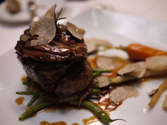 Succulent beef fillet topped with truffles, served with green beans and carrots on a fine dining plate.