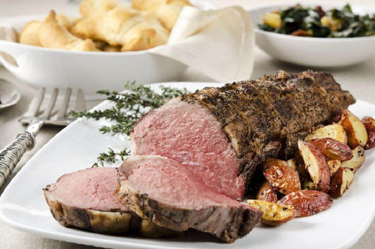 Succulent Swiss-style beef dish with roasted potatoes and fresh herbs on a white plate.