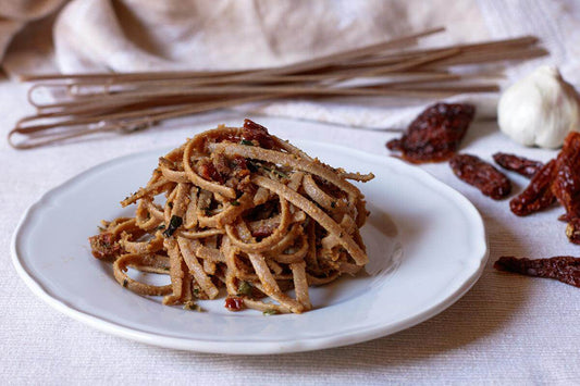 Delicious struncatura alla calabrese pasta served on a white plate with sun-dried tomatoes and garlic.