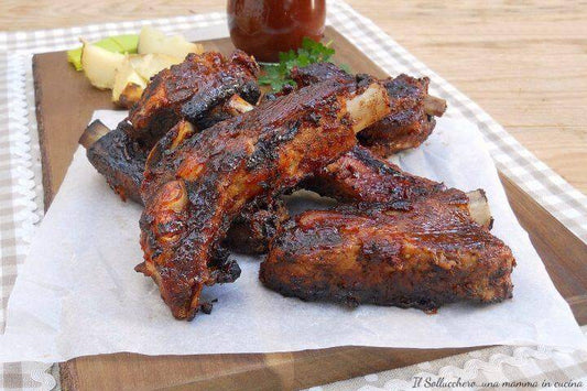Succulent grilled pork ribs on parchment paper, garnished with herbs and lemon, served on a wooden board.