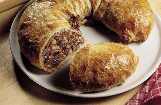 Delicious presnitz pastry with a rich filling of nuts and dried fruits on a plate.