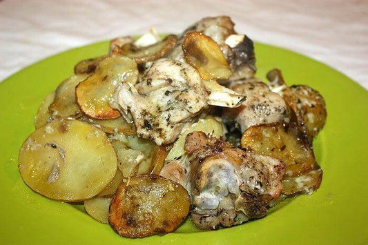 Delicious lamb shoulder with potatoes, seasoned with herbs on a bright green plate.