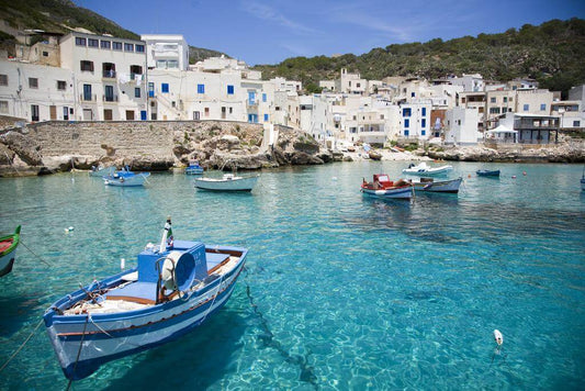 Porticciolo di Levanzo con barche colorate nel mare cristallino e case bianche sullo sfondo.