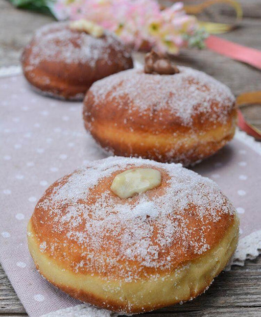 Delicious homemade Peschette dolci with powdered sugar and filling on a decorative tablecloth.