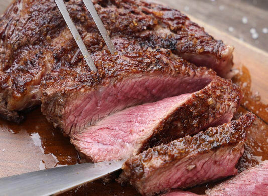 Sliced roasted beef filet with a crispy crust, showcasing juicy pink interior on a wooden cutting board.