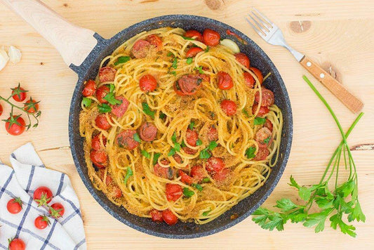 Delicious vermicelli pasta dish with cherry tomatoes and parsley in a skillet.