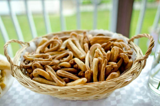 Wicker basket filled with freshly baked, twisted bread sticks on a table.