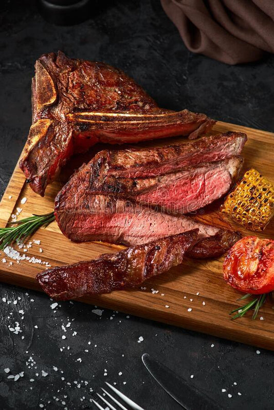 Deliciously grilled costata di manzo on a wooden board with fresh herbs, grilled tomato, and corn.