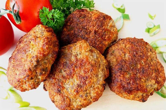 Delicious Sicilian eggplant meatballs garnished with fresh parsley and tomatoes on a wooden surface.