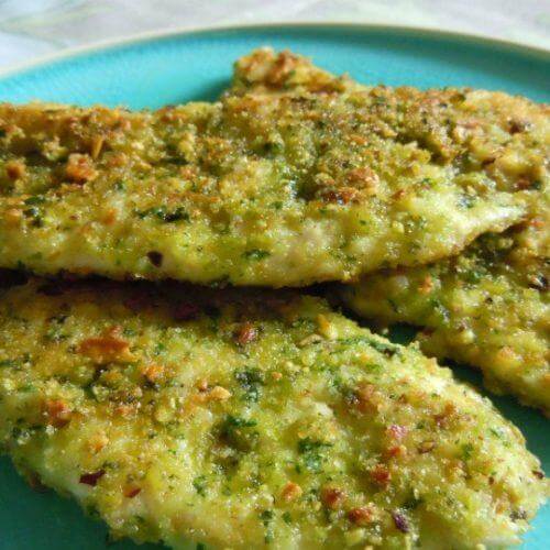 Crispy baked fish fillets coated in herbs and breadcrumbs on a teal plate.