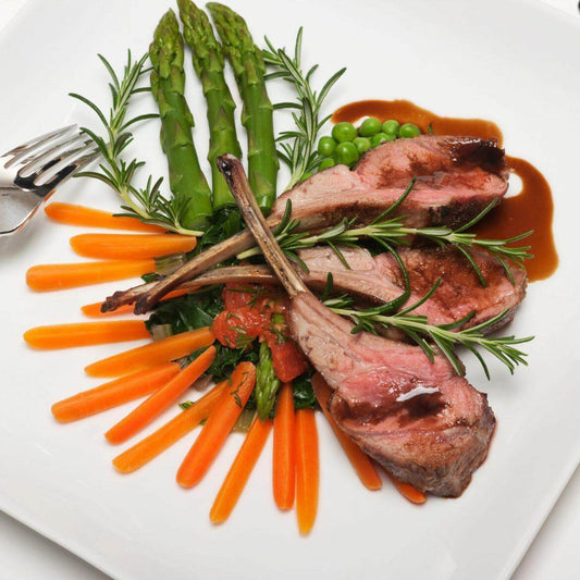 Delicious lamb shoulder with asparagus, carrots, and a rich sauce, garnished with fresh rosemary.