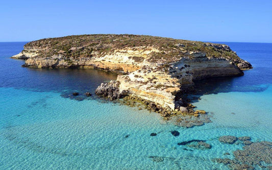Stunning view of a rocky island surrounded by crystal clear turquoise waters near Lampedusa.