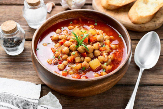 Zuppa di ceci in un ciotola di legno, servita con fette di pane tostato e decorata con prezzemolo.