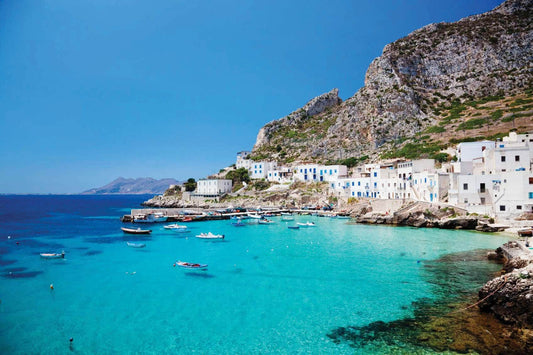 Scenic view of Alicudi island with crystal clear waters and traditional white buildings along the coast.