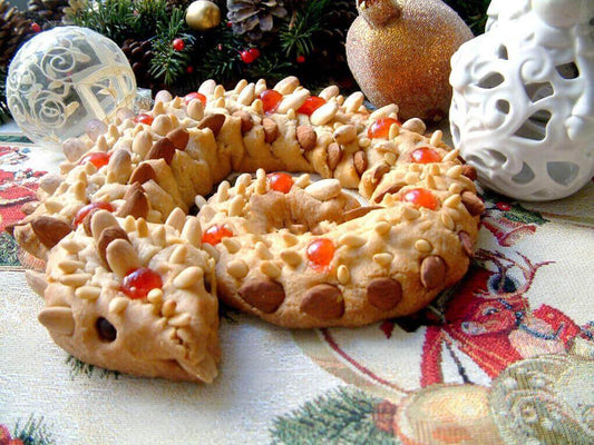 Decorative almond cookie shaped like a serpent, adorned with nuts and colorful candied fruits, festive table setting.