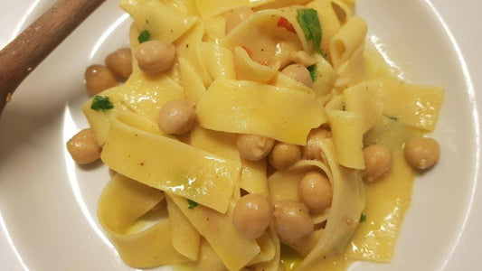 Pasta tagliatelle with chickpeas garnished with parsley on a white plate.