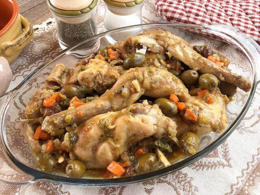 Delicious rabbit stew alla cacciatora with vegetables and olives served in a glass dish.