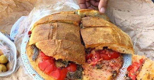 Pane Cunzato alla Calabrese, una pagnotta farcita con pomodoro e altre delizie, servita su un piatto tradizionale.