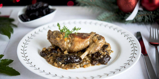 Delicious rabbit cooked in white wine with mushrooms, garnished with herbs, served on an elegant table setting.