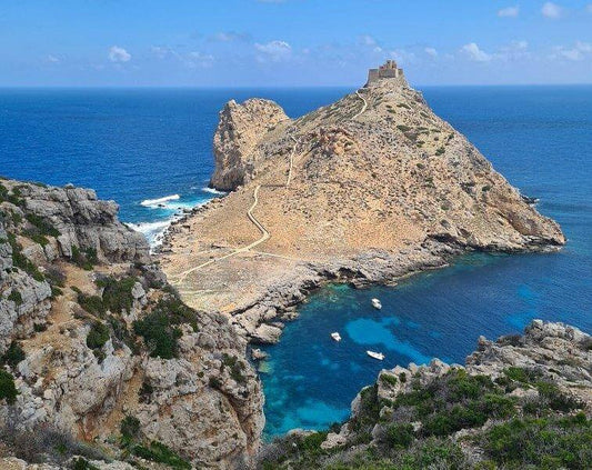 Scenic view of Marettimo island with rocky cliffs and ancient castle overlooking the blue Mediterranean Sea.