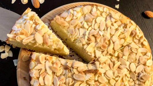 Delicious torta di mandorle with almond slices on top, freshly cut slice on a wooden platter.