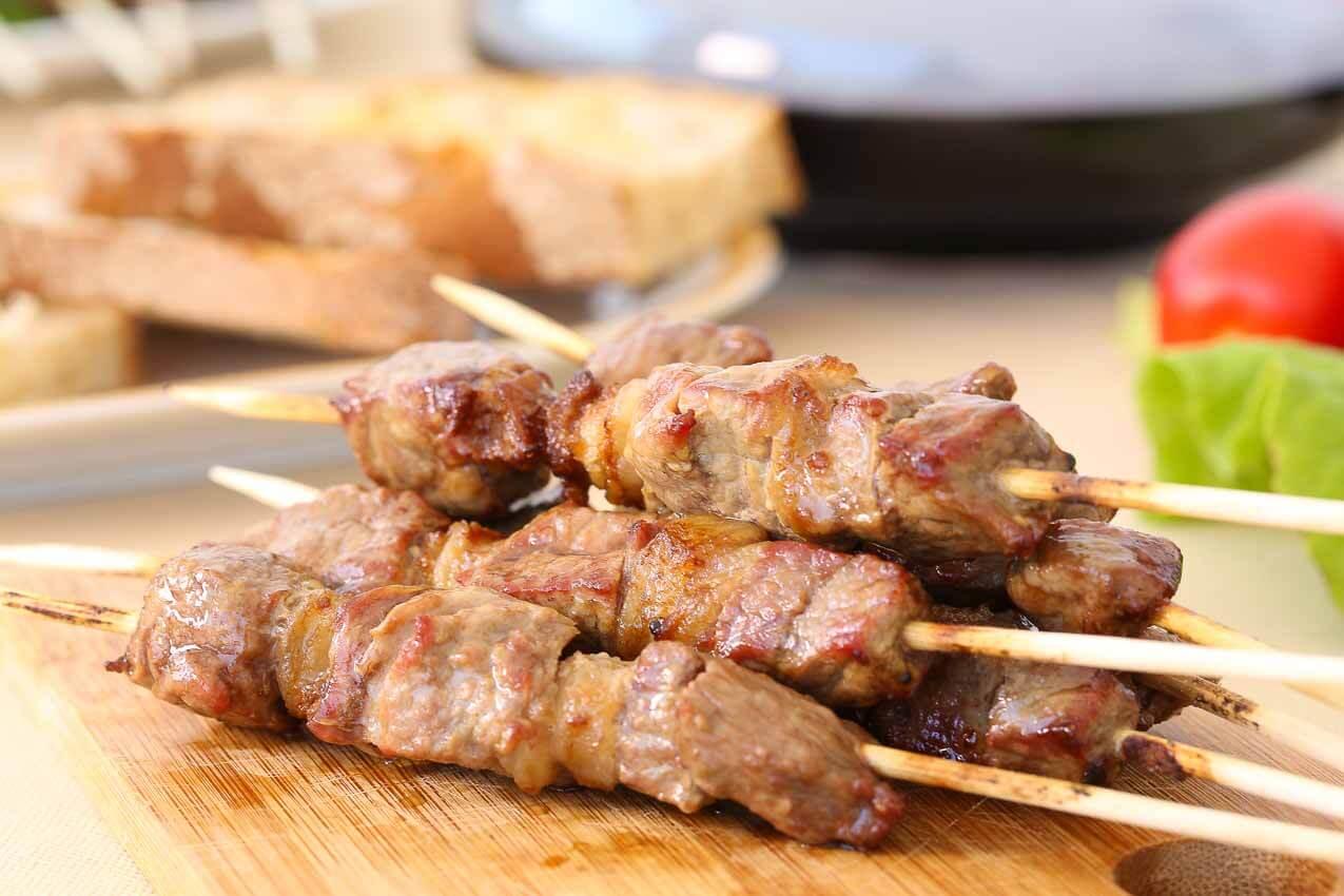 Arrosticini di Pecora, traditional Abruzzese lamb skewers served on a wooden board, perfect for grilling.