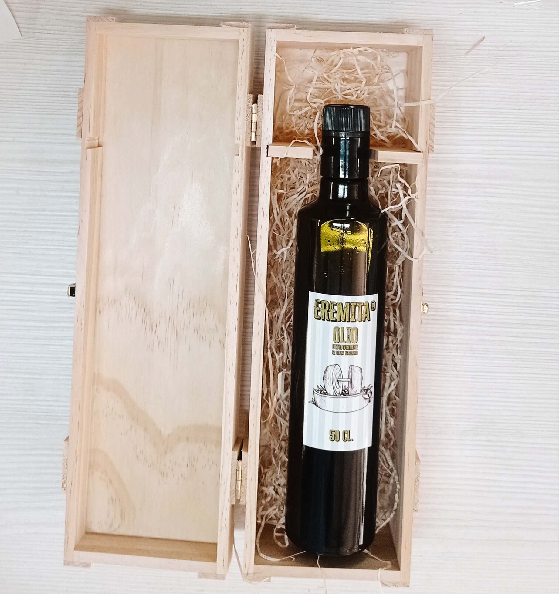 Bottle of Eremita extra virgin olive oil 50 cl in a wooden box with straw decoration.