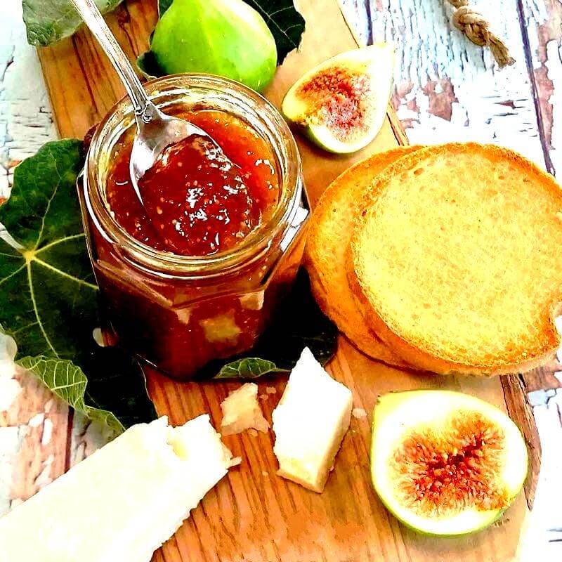 Salsa Salata di Fichi di Calabria in a jar, served with cheese, toasted bread, and fresh figs on a wooden board.
