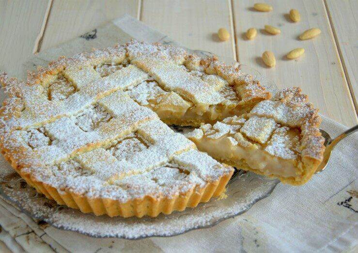 Crostata artigianale con crema di mandorla, decorata con zucchero a velo e pinoli.