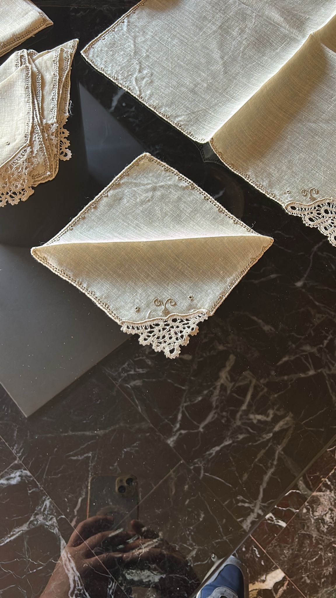 Set of vintage Burano lace napkins displayed on a dark marble table, showcasing intricate craftsmanship.