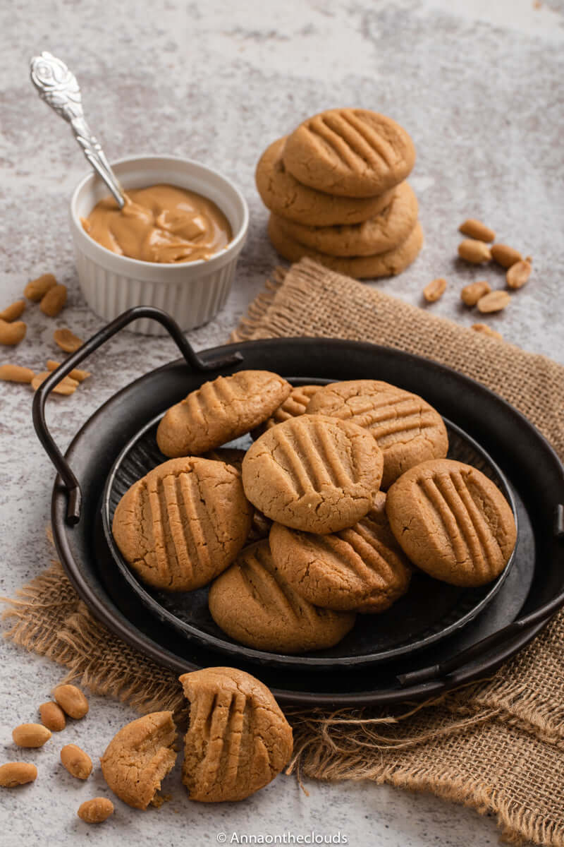 Delicious Dolci Amaretti al Bergamotto cookies on a black plate with almond spread, showcasing their rich texture.