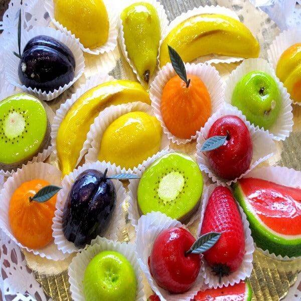 Colorful Sicilian Martorana fruit sweets shaped like real fruits on a decorative platter.