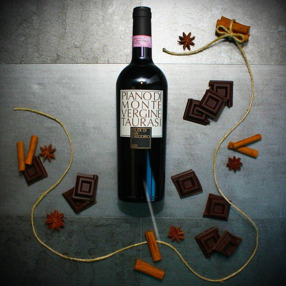 Taurarsi - Vino Rosso Campania DOCG bottle surrounded by chocolate and spices on a textured surface.