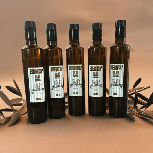 Five bottles of Eremita premium extra virgin olive oil, 50 cl each, surrounded by olive leaves.