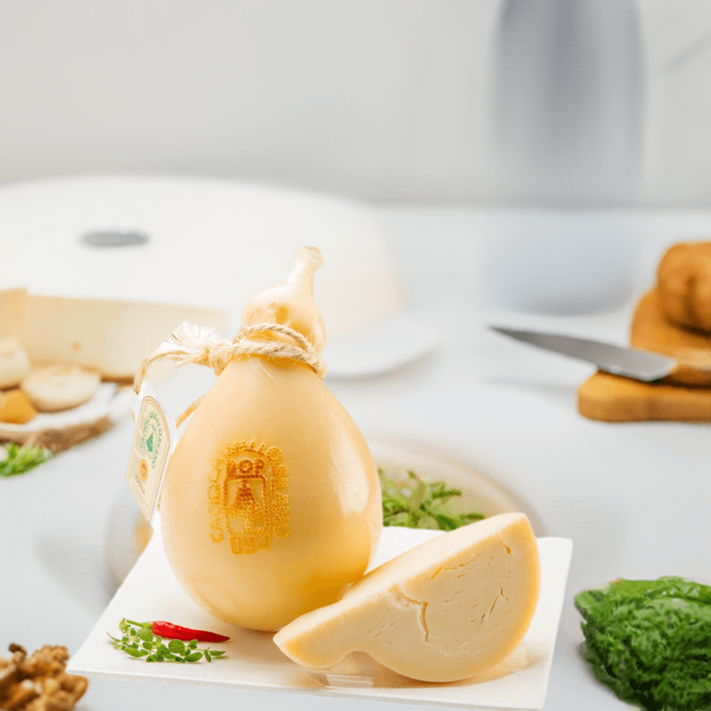Caciocavallo Silano DOP cheese, pear-shaped, semi-aged with a buttery and spicy flavor, displayed with a serving slice.
