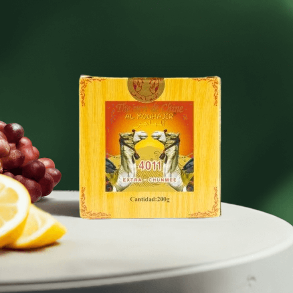 Al Mouhajir Thè Verde Cinese 200g box with chunmee tea and fresh lemons on a table.