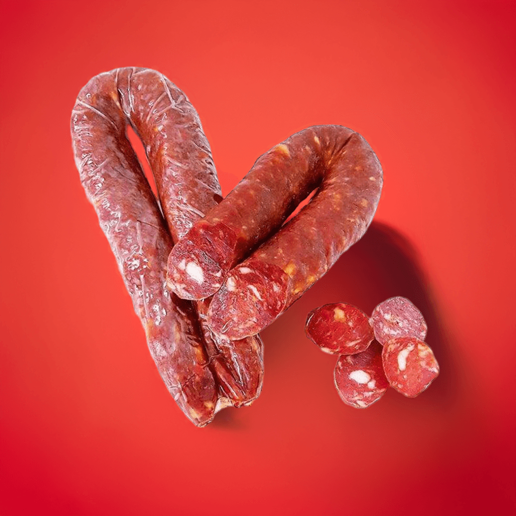 Salsiccia Curva Calabrese unica al monto per gusto e piccantezza su sfondo rosso.