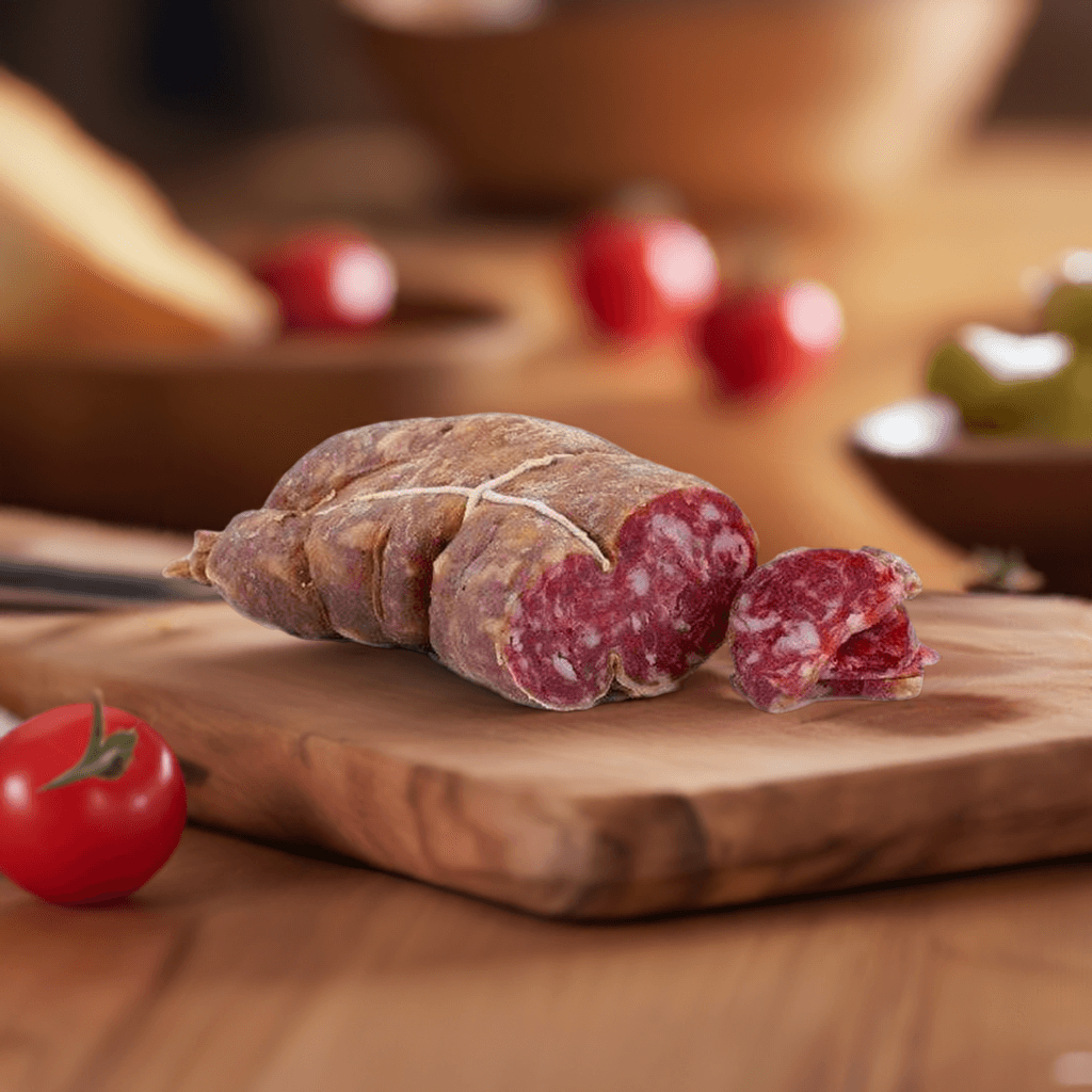 Soppressata Grecanica Calabrese stagionata naturalmente e affumicata su un tagliere di legno con pomodori freschi.