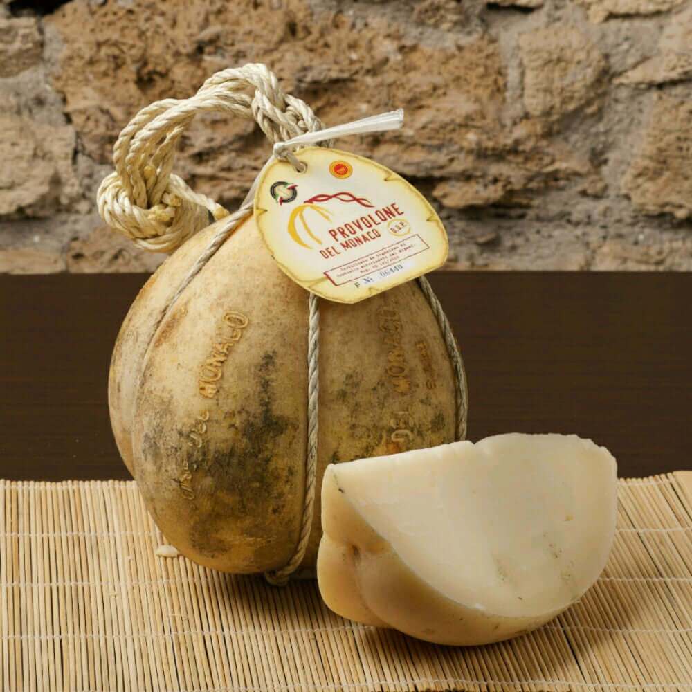 Provolone del Monaco DOP cheese from Monti Lattari with a pear shape, aged 24 months, displayed on a bamboo mat.