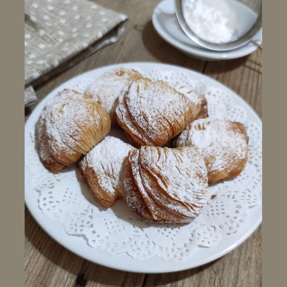Sfogliatella Riccia on a lace plate, dusted with powdered sugar, showcasing their flaky texture and artisanal quality.