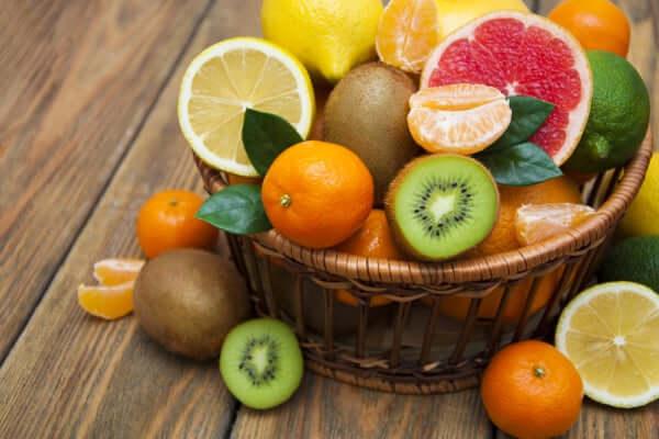Basket of seasonal mixed fruits including citrus, kiwi, and mandarins, freshly harvested from local producers.