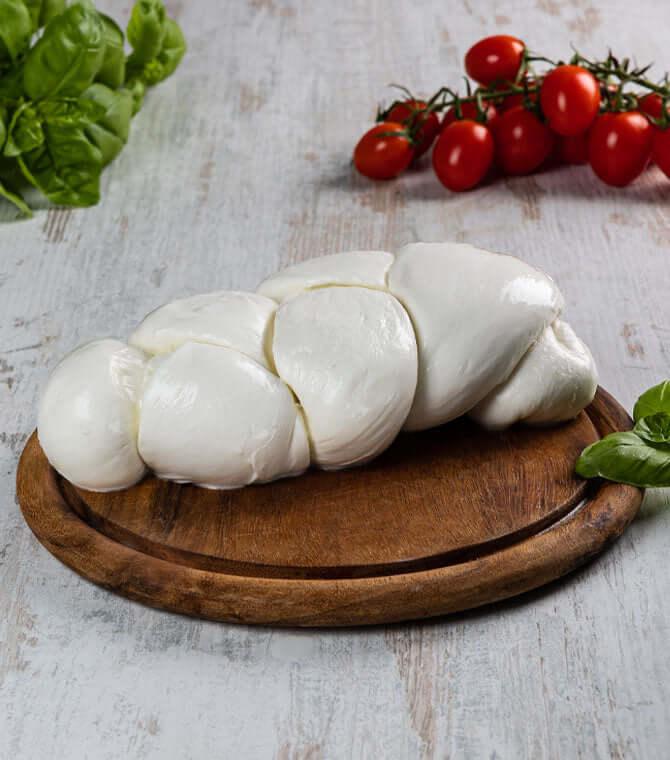 Mozzarella fior di latte 1 kg, handmade braided cheese on a wooden platter with cherry tomatoes and basil.