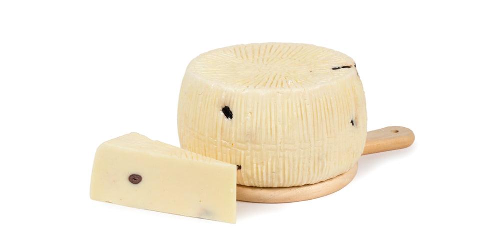 Primo sale con Olive Nere formaggio siciliano su tagliere con pezzo a lato.