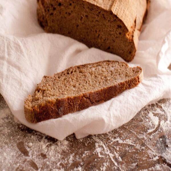 Pane di Jurmanu, pane di segale calabrese con crosta scura e fetta su tovagliolo bianco.