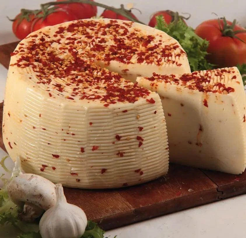 Formaggio di Pecora al Peperoncino - Sicilian cheese with chili, sliced and displayed on a wooden board.
