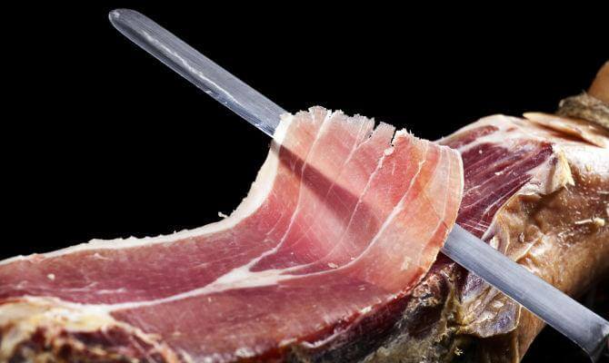 Prosciutto Crudo Calabrese sliced for serving, showcasing its rich color and texture, ideal for antipasti.