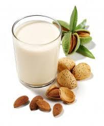 Pasta di Mandorla and almond milk in a glass with whole and cracked almonds.