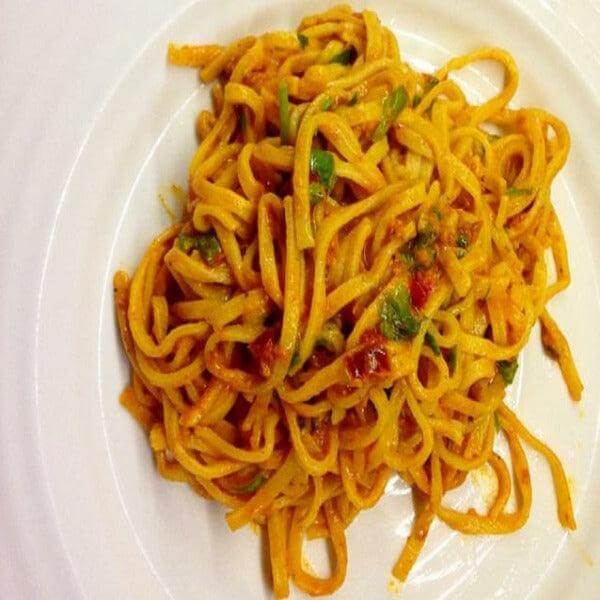Delicious pasta dish featuring colorful vegetables and rich sauce on a white plate.