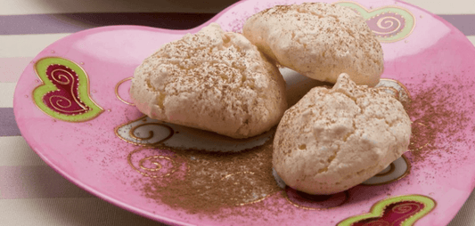 Delicate Sospirus cookies dusted with cocoa on a pink heart-shaped plate.