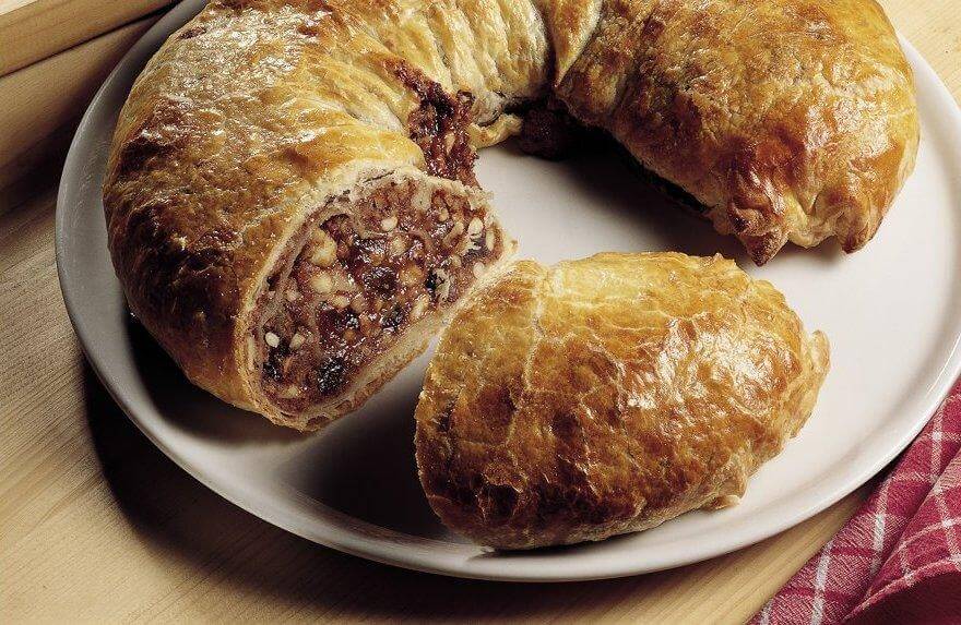 Delicious presnitz pastry with a rich filling of nuts and dried fruits on a plate.